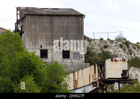 Asbest verkleideter shoreham-Zement arbeitet jetzt verfällt mit Stütztürmen und Förderern gebrochene Fenster und Asbestplatten ein braunes Feld-Gelände eingezäunt Stockfoto