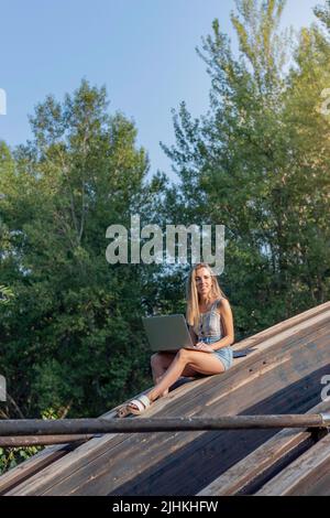 Vertikale Ansicht der jungen Frau, die im Sommer als digitale Nomade arbeitet, umgeben von Natur und Kopierraum Stockfoto