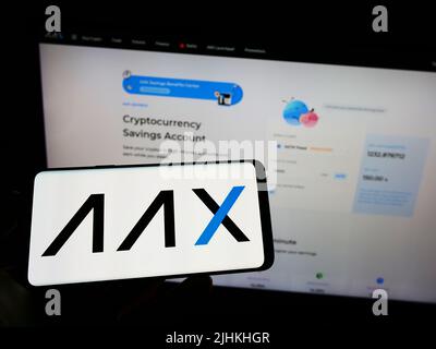 Person, die Mobiltelefon mit dem Logo der Kryptowährungsfirma AAX Limited auf dem Bildschirm vor der Business-Webseite hält. Konzentrieren Sie sich auf die Telefonanzeige. Stockfoto