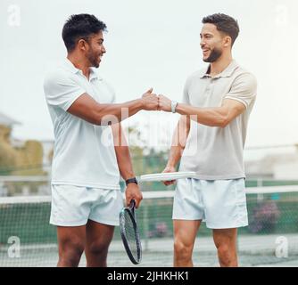 Zwei lächelnde ethnische Tennisspieler, die vor dem Spiel auf dem Platz mit Faust Fistbump geben. Passen Sie Athleten Team stehen und mit Handgesten für viel Glück Stockfoto