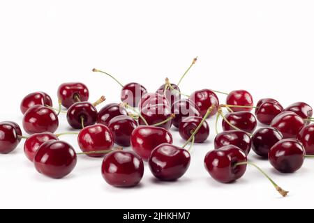 Viele reife Kirschen auf hellem Hintergrund verstreut. Nahaufnahme. Stockfoto