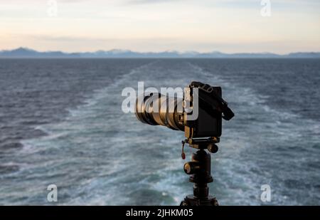 Professionelle dslr auf Stativ auf der Rückseite eines von der Küste Alaskas abfahrenden Kreuzschiffs, das aufwacht Stockfoto