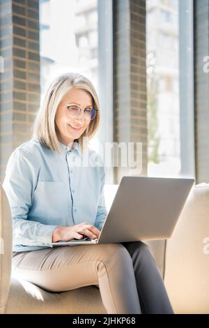 Ältere Frau arbeitet als Freiberuflerin am Laptop in einem Coworking. Stockfoto