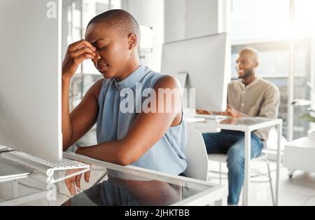 Junge gestresste afroamerikanische Geschäftsfrau, die bei der Arbeit an einem Desktop-Computer unter Kopfschmerzen leidet. Eine unglückliche schwarze Hündin Stockfoto
