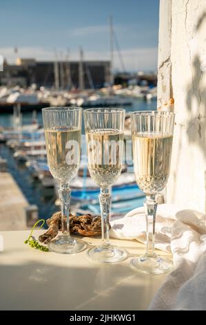 Drei Gläser französischer Champagner Sekt und Blick auf bunte Fischerboote im alten Hafen von Cassis, Provence, Frankreich, Sommerfest in PR Stockfoto