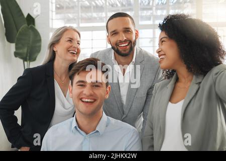 Eine Gruppe von vier fröhlichen, vielfältigen und positiven Geschäftsleuten, die zusammen ein Selfie bei der Arbeit machen. Glückliche hispanische Geschäftsfrau, die mit ihr ein Foto macht Stockfoto