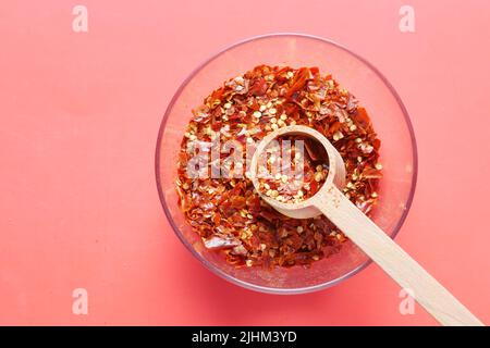 Rote Chilischote Flocken auf rotem Hintergrund Stockfoto