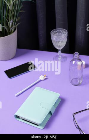 Kreatives Layout mit Papeterie, Kaffeetasse und Smartphote auf violettem Tisch Stockfoto