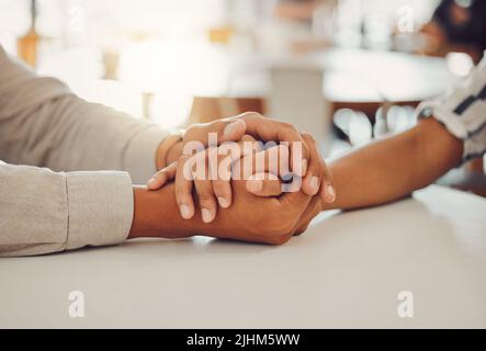 Nahaufnahme eines jungen Mannes und einer Frau, die Hände an einem Holztisch halten, von oben. Liebevolles Paar, das Empathie, Verständnis und Vertrauen in ihre ausdrückt Stockfoto
