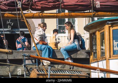 Mädchen trinken Wein auf einem hölzernen Dock oder Pier auf einem Kanal in Kopenhagen, Dänemark Stockfoto