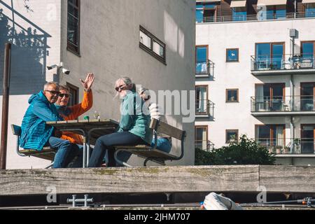 Freunde trinken Wein und Bier am Tisch auf einem hölzernen Dock oder Pier auf einem Kanal in Kopenhagen, Dänemark Stockfoto