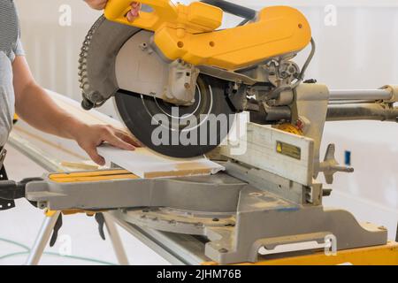 Bauarbeiter schneidet Holzleisten-Schonplatte an der Gehrungsäge Stockfoto