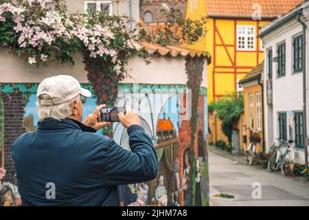 Schöne Straße in der Altstadt von Helsingør, Dänemark, mit alten bunten traditionellen Häusern und Wandgemälden mit Touristen, die Fotos machen Stockfoto
