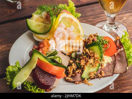 Traditionelle dänische Smørrebrød oder offene Sandwiches auf einem Teller, Roastbeef mit Remoulade, Tomaten und geriebenem Meerrettich auf dänischem Roggenbrot Stockfoto