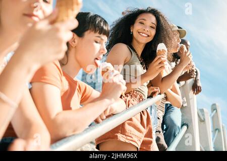 Der beste Tag aller Zeiten. Beschnittenes Porträt einer attraktiven jungen Frau, die mit ihren Freundinnen am Strand ein Eis genießt. Stockfoto