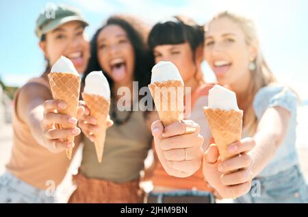 Die Saison, auf die sie gewartet haben. Beschnittenes Porträt einer Gruppe attraktiver junger Freundinnen, die am Strand Eis genießen. Stockfoto
