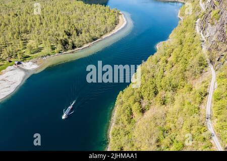 Luftaufnahme des Lovatn-Sees, lokales Schiff auf dem Weg nach Kjenndalstova, Schotterbergstraße über dem See, Norwegen. Stockfoto