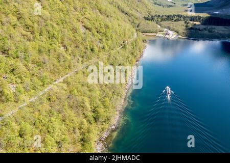 Luftaufnahme des Lovatn-Sees, lokales Schiff auf dem Weg nach Kjenndalstova, Schotterbergstraße über dem See, Norwegen. Stockfoto