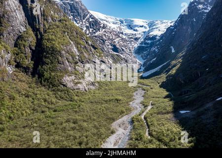 Luftaufnahme über Tal und Schotterbergstraße zum Gletscher Kjenndalsbreen im Hintergrund, Norwegen. Stockfoto