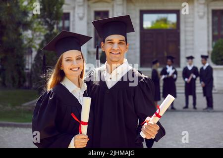 Porträt von glücklich lächelnden Universitätsfreunden mit Diplomen am Abschlusstag Stockfoto