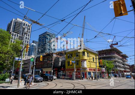 Chaotische Straßenszene mit einer eklektischen Gruppe von Gebäuden und Deckenkabeln an der Ecke Queen St East und Church St im Zentrum von Toronto, Ontario, Kanada. Stockfoto