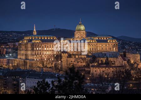 Budapest, Ungarn - der schöne Budaer Burg (Königlicher Palast) vom Gellertberg beleuchtet in der Winterzeit zur blauen Stunde gesehen Stockfoto