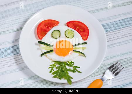 Das sonnige Eierfrühstück mit Tiercharakter ist für Kinder eingerichtet. Serviert mit Gemüse. Stockfoto