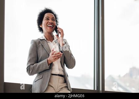 Nahaufnahme einer Geschäftsfrau mit einem Gespräch auf dem Smartphone. Glückliche weibliche Geschäftsführerin trägt formelle Kleidung. Sie arbeitet in einem Unternehmensbüro. Stockfoto