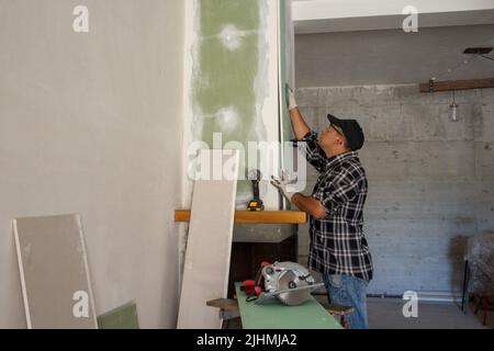 Abbildung eines Handwerkers, der Trockenbauplatten installiert. Do-it-yourself manuelle Arbeit der Renovierung eines Kamins und Hauswände Stockfoto