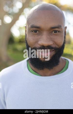 Vertikales Bild eines glücklichen afroamerikanischen Mannes, der vor der Kamera lächelt Stockfoto