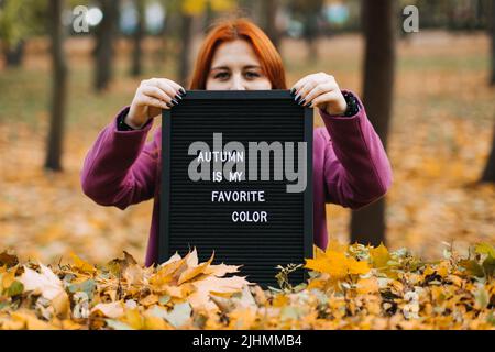 Hallo Herbst. Rotes Haar Mädchen mit Brief Message Board mit Text Herbst ist meine Lieblingsfarbe Stockfoto