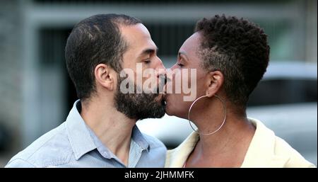 Interrassisches Paar küsst sich gegenseitig, afrikanische Frau und hispanischer Ehemann küssen sich draußen Stockfoto