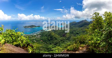 Panorama der Insel Mahe, Seychellen, Küste von Morne Blanc Aussichtspunkt mit üppiger tropischer Vegetation, kristallblauem Ozean und kleiner tropischer Insel Stockfoto