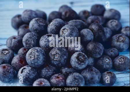 Haufen frischer roher Heidelbeeren mit Wassertropfen auf blauem Hintergrund Stockfoto