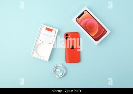 Tjumen, Russland-18. Juli 2022: IPhone 12 mini Produkt rot mit Einzelhandelsverpackung. Draufsicht, blauer Hintergrund Stockfoto