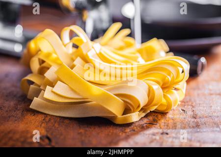 Ungekochte Pappardelle auf einem Holztisch. Stockfoto