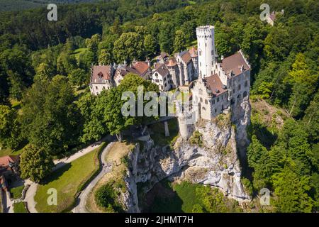 Luftaufnahme von schloss lichtenstein auf bewaldeten Felsklippen in den Schwäbischen Alpen im Sommer. Saisonales Panorama des romantischen Märchenpalastes in Gothi Stockfoto