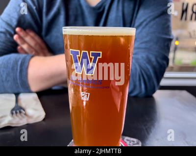 Seattle, WA USA - ca. Juni 2022: Nahaufnahme eines schaumigen Bieres in einem Glas der University of Washington in einer lokalen Bar. Stockfoto