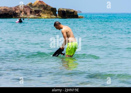 Junger Araber, der in der Nähe des Strandes im Mittelmeer steht. Konzept für Sommerferien. Stockfoto