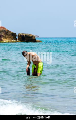 Junger Araber, der in der Nähe des Strandes im Mittelmeer steht. Konzept für Sommerferien. Stockfoto