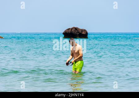 Junger Araber, der in der Nähe des Strandes im Mittelmeer steht. Konzept für Sommerferien. Stockfoto