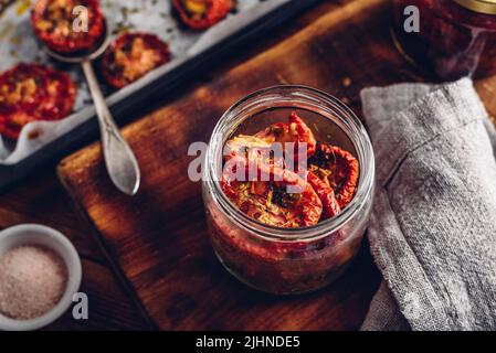 Frisch gekochte sonnengetrocknete Tomaten mit Oregano und Öl in einem Glasglas Stockfoto