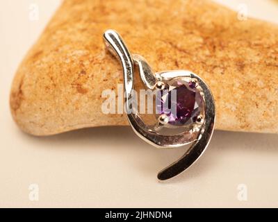 Nahaufnahme eines Pendelstegs aus Weißgold mit glänzendem purpurem Stein Stockfoto