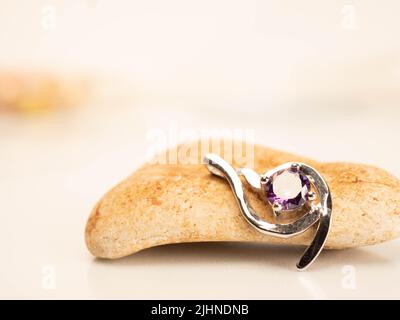 Nahaufnahme eines Pendelstegs aus Weißgold mit glänzendem purpurem Stein Stockfoto