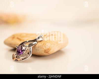 Nahaufnahme eines Pendelstegs aus Weißgold mit glänzendem purpurem Stein Stockfoto