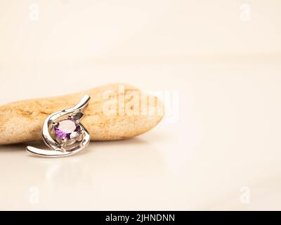 Nahaufnahme eines Pendelstegs aus Weißgold mit glänzendem purpurem Stein Stockfoto