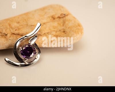 Nahaufnahme eines Pendelstegs aus Weißgold mit glänzendem purpurem Stein Stockfoto