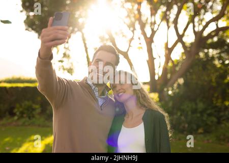Bild eines glücklichen kaukasischen Paares, das Selfie im Garten macht Stockfoto