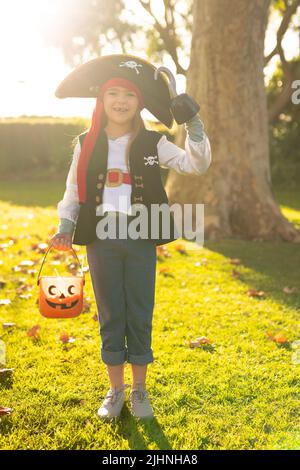 Vertikales Bild eines glücklichen kaukasischen Jungen im Piratenkostüm im Herbstgarten Stockfoto