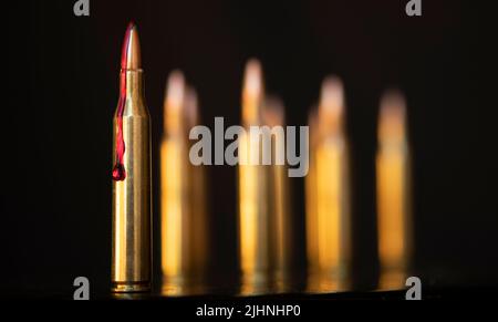 AR-15-Stil Gewehrpatrone und Blut (Fototafel). Stockfoto